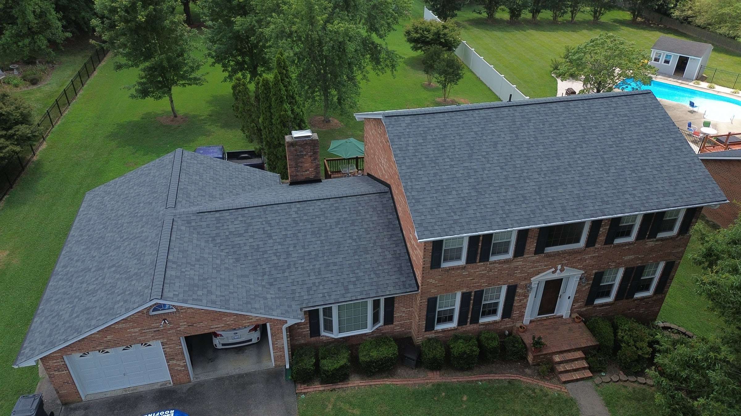 Two-story brick colonial with a new gray architectural shingle roof over the house and the garage wing.