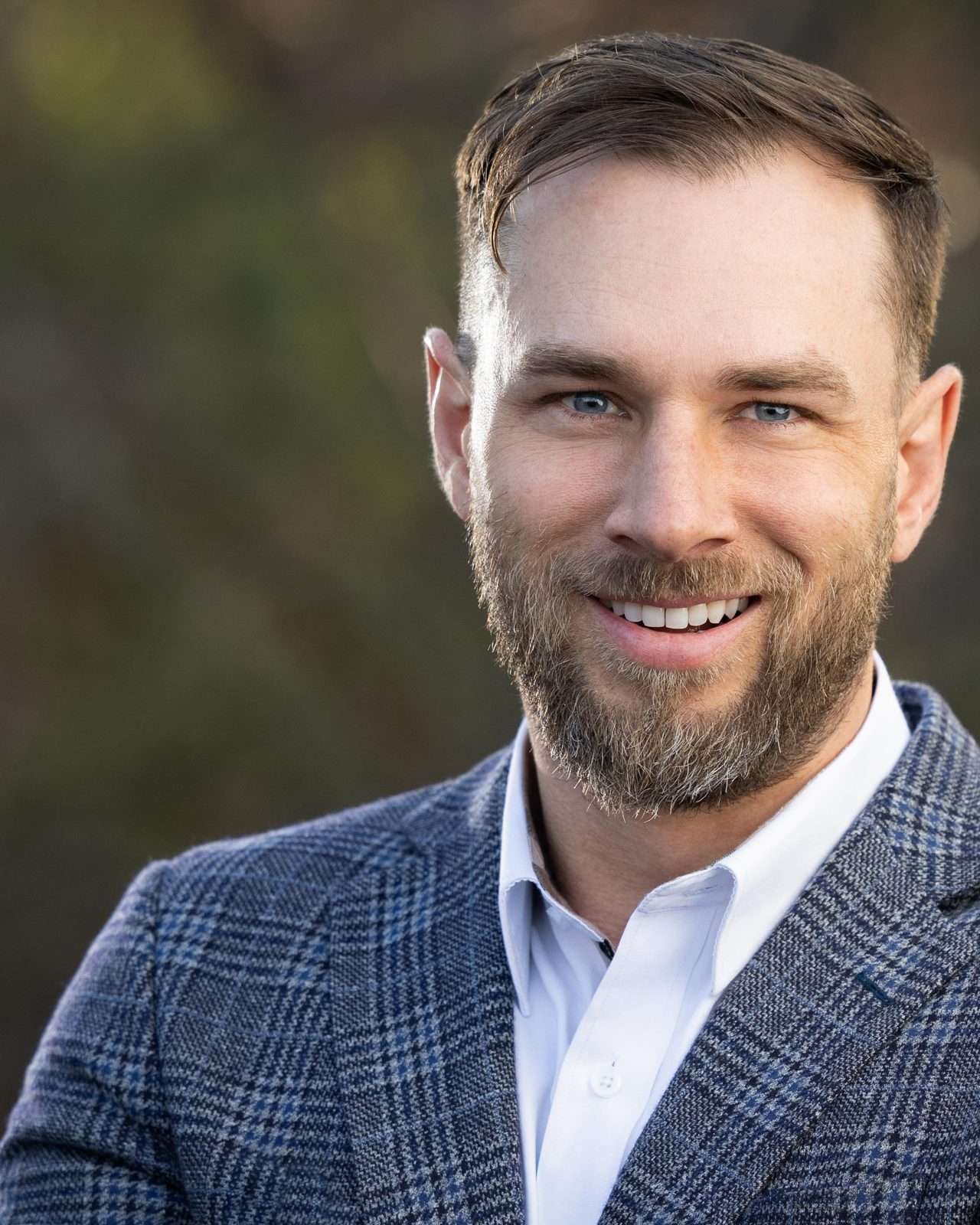 Portrait of Cole Haynes, owner of Escalade Roofing, smiling, in a checked blazer.