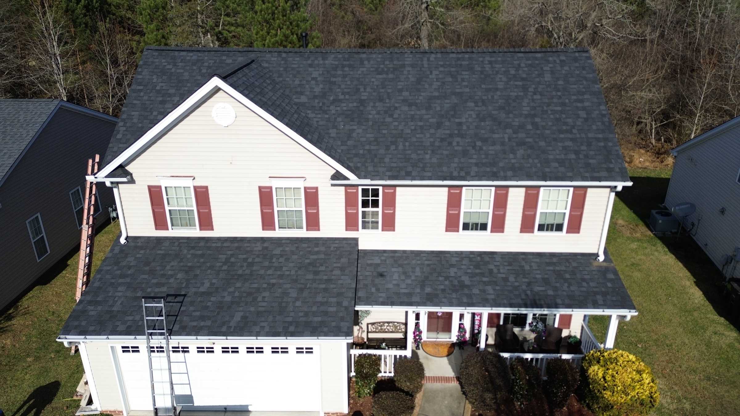 A two-story white house with red shutters and a new dark shingle roof, seen from the front.