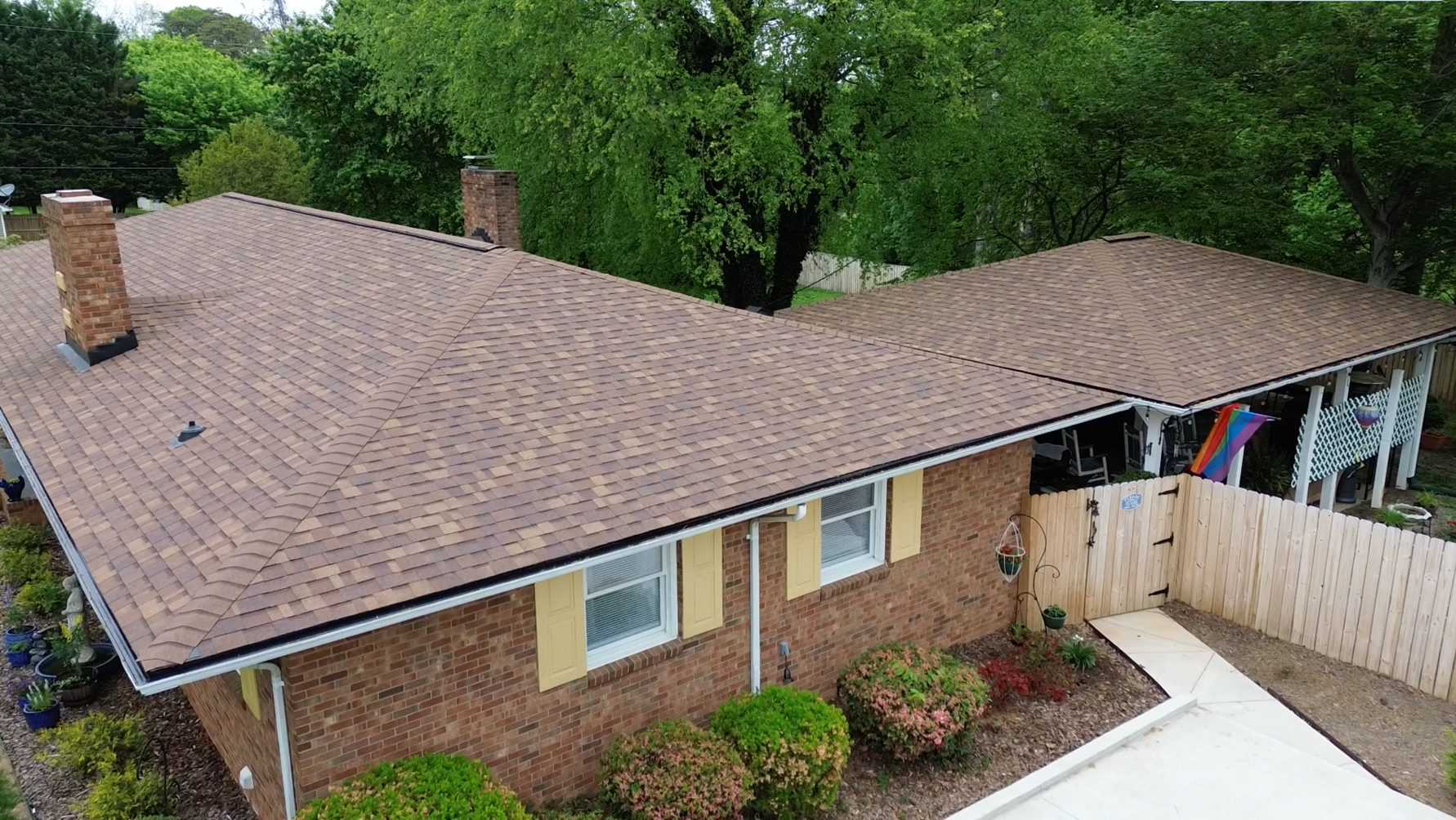 A brick ranch house with a new brown shingle roof.